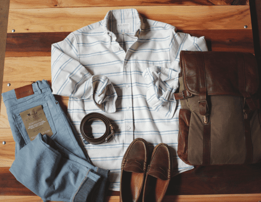 white flannel shirt laid out with jeans, loafers, belt and canvas designer bag